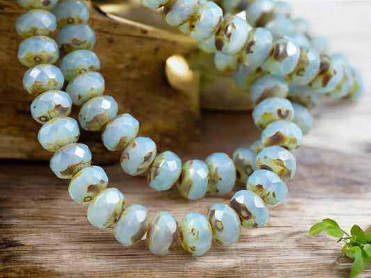 A series of blue opal picasso fire polished rondelle beads, approximately 3x5mm in size, displayed on a wooden surface.